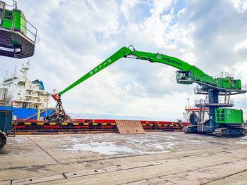 870 E Leistungsstark im Hafenumschlag SENNEBOGEN 870 E Hafenumschlagbagger bewegt Metallschrott mit einem Greifer beim Schiffsumschlag im Hafen von Hereke.