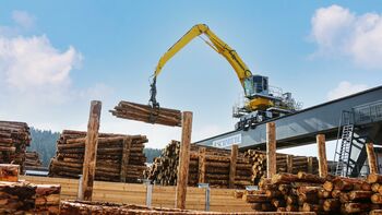 Einsatz in hochmodernem Holzwerk: Elektrobagger auf Schienenportal verlädt Rundholz