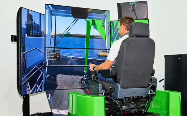 Besucher steuert am SENNEBOGEN Loghandling-Simulator den virtuellen Holzumschlag auf mehreren Bildschirmen.
