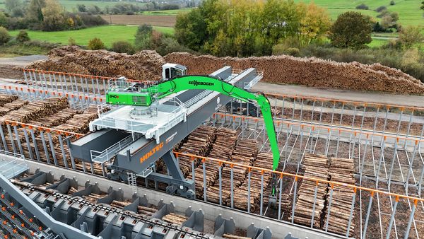 SENNEBOGEN 840 E beim Aufgeben von Rundholz auf die HOLTEC-Anlage am automatisierten Rundholzplatz.